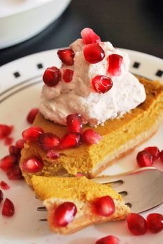 a slice of pumpkin pie with whipped cream and pomegranates on top