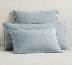 three light blue pillows stacked on top of each other in front of a white wall