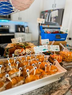 an assortment of food items displayed on trays at a buffet table in a kitchen