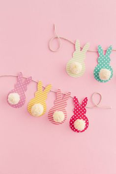 some paper bunnies are hanging on a pink background with polka dots and white pom poms