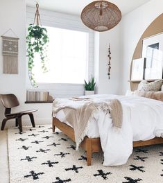 a bed room with a neatly made bed next to a window and a rug on the floor