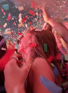 a woman standing in front of confetti and streamers with her phone to her ear