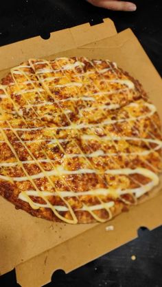 a pizza sitting on top of a cardboard box covered in cheese and melted cheese toppings