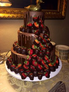 a triple layer chocolate cake with strawberries on the top and bottom, sitting on a table