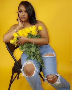 a woman sitting on a chair with flowers in her lap and looking at the camera