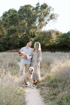 a man and woman walking with a dog on a path