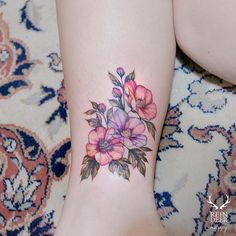 a close up of a person's foot with flowers tattooed on the side of her leg