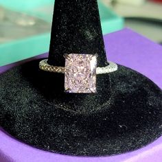 a diamond ring sitting on top of a black velvet hat stand in a jewelry store