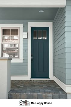 a blue front door on a green house with white trim and window sill in the foreground