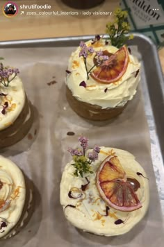 four cupcakes are decorated with fruit and flowers