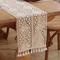 a lace table runner with tassels sits on a dining room table