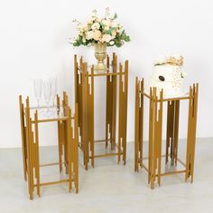 three wooden tables with vases and glasses on them in front of a white wall