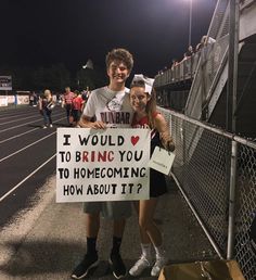 two people holding a sign that says i would bring you to home coming how about it?