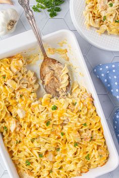 a casserole dish with chicken and noodles in it on a table next to garlic