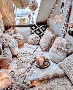 a couch with pillows, blankets and lights on it in front of a window filled with balloons