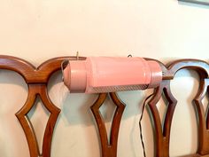 a pink hair dryer sitting on top of a wooden rack next to a wall