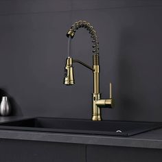 a kitchen sink with brass faucet and black countertop