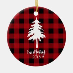 a red and black plaid christmas ornament with a white tree on the front