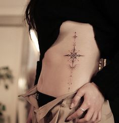 a woman's stomach with a small star tattoo on her lower side ribcage