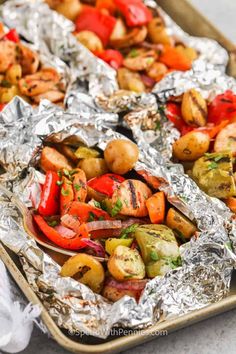 roasted vegetables in foil lined up on a baking sheet