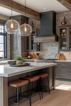 a kitchen island with stools and lights hanging from the ceiling