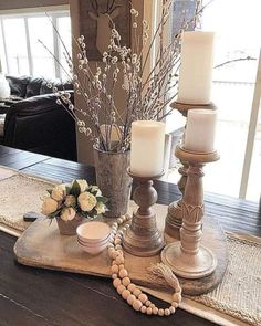 a table with candles, flowers and beads on it in front of a couches window