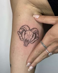 a woman's arm with a tattoo on it that has two rams in the shape of a heart