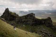 two people standing on top of a grass covered hill