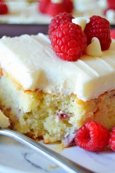 a piece of cake with white frosting and raspberries on top