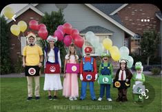 a group of people standing in front of a house with balloons and mario costume on