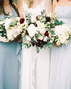 three bridesmaids in blue dresses holding bouquets