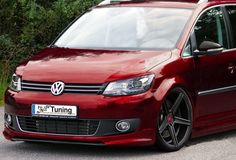 a red vw touran parked in front of some trees