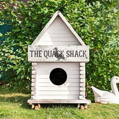 the quack shack is next to a swan and duck in front of some bushes