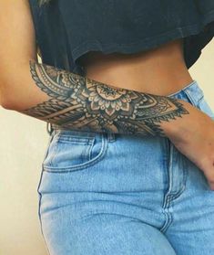 a woman with a tattoo on her arm is holding something in her hand while wearing blue jeans