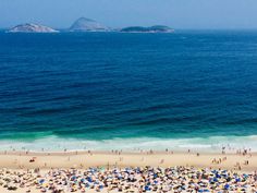 many people are on the beach with umbrellas and blue water in the background as seen from above