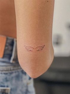 a small tattoo on the leg of a woman's left arm, with wings drawn across it