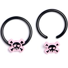 two pairs of black and pink skull and crossbones ear rings on white background