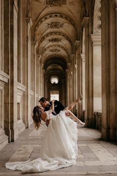 a bride and groom are kissing in an old building with columns on either side of them