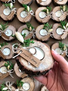 a person holding a piece of wood with candles in it and tags on the top