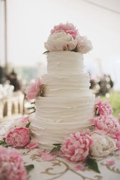 a white wedding cake with pink flowers on the table