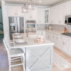 a large kitchen with white cabinets and an island in the middle is decorated with flowers