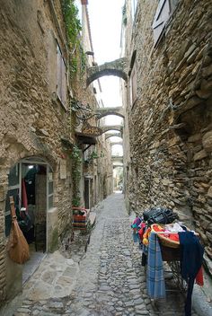 an alleyway with stone walls and cobblestone floors, clothes hanging out to dry