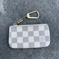 a white purse with a gold keychain hanging from it