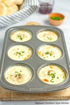 a muffin tin filled with baked food on top of a wooden cutting board