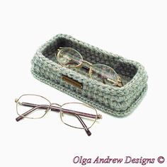 a pair of glasses sitting in a crocheted case next to a pair of reading glasses