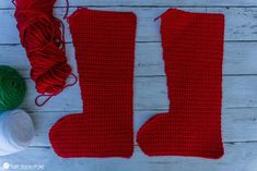 two red knitted stockings next to some yarn