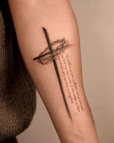 a person with a tattoo on their arm holding a cross and the words above it