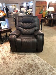 a brown recliner chair sitting on top of a rug in a room filled with furniture