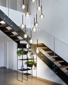 a bunch of lights hanging from the side of a stair case next to a banister