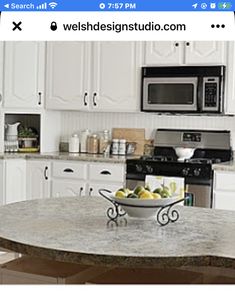 a bowl of fruit is sitting on the counter in front of an oven and microwave